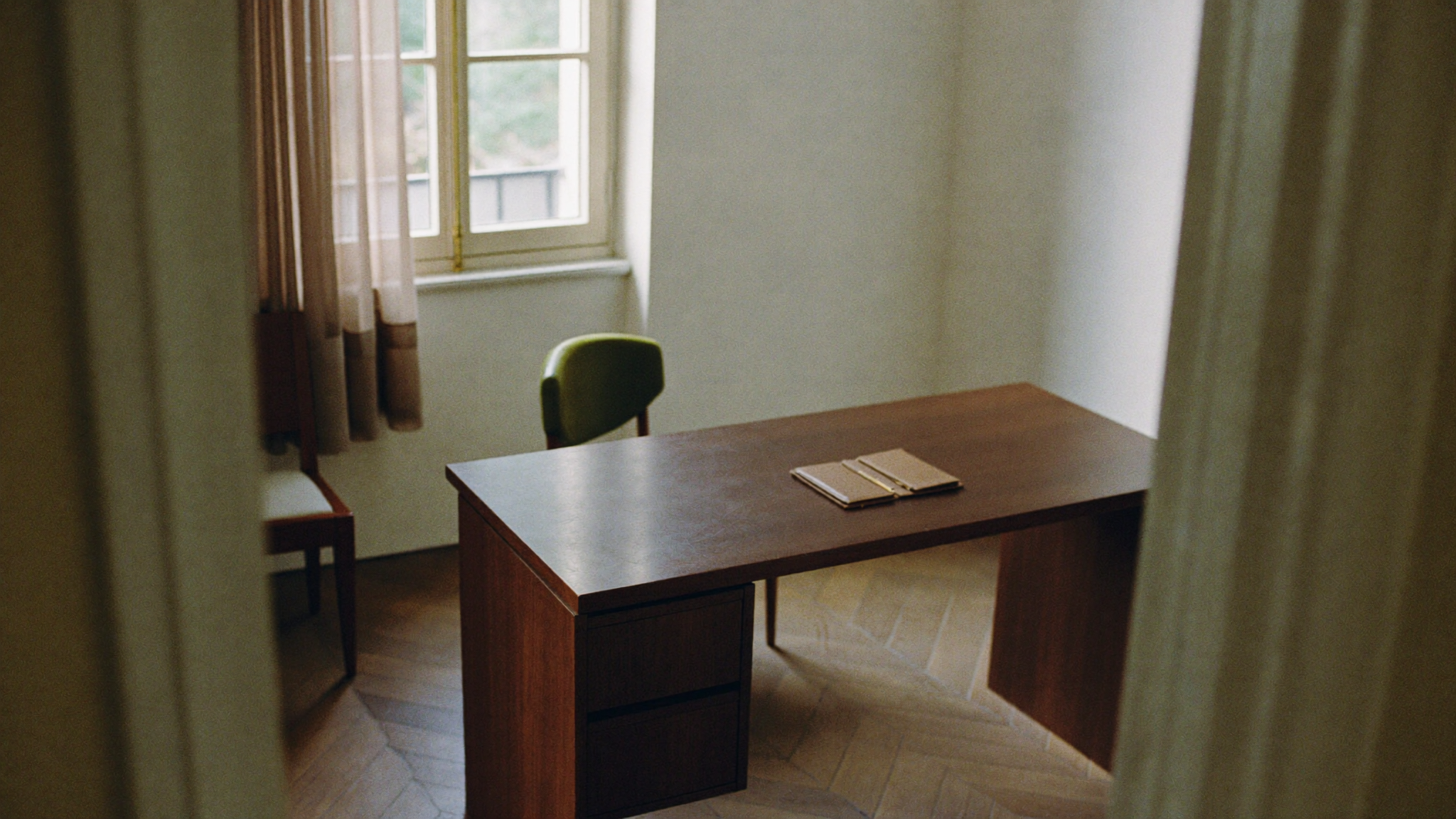 Minimalistisches Treuhandbüro mit Nussbaumschreibtisch im Morgenlicht, geschlossenem Ledger und Brieföffner