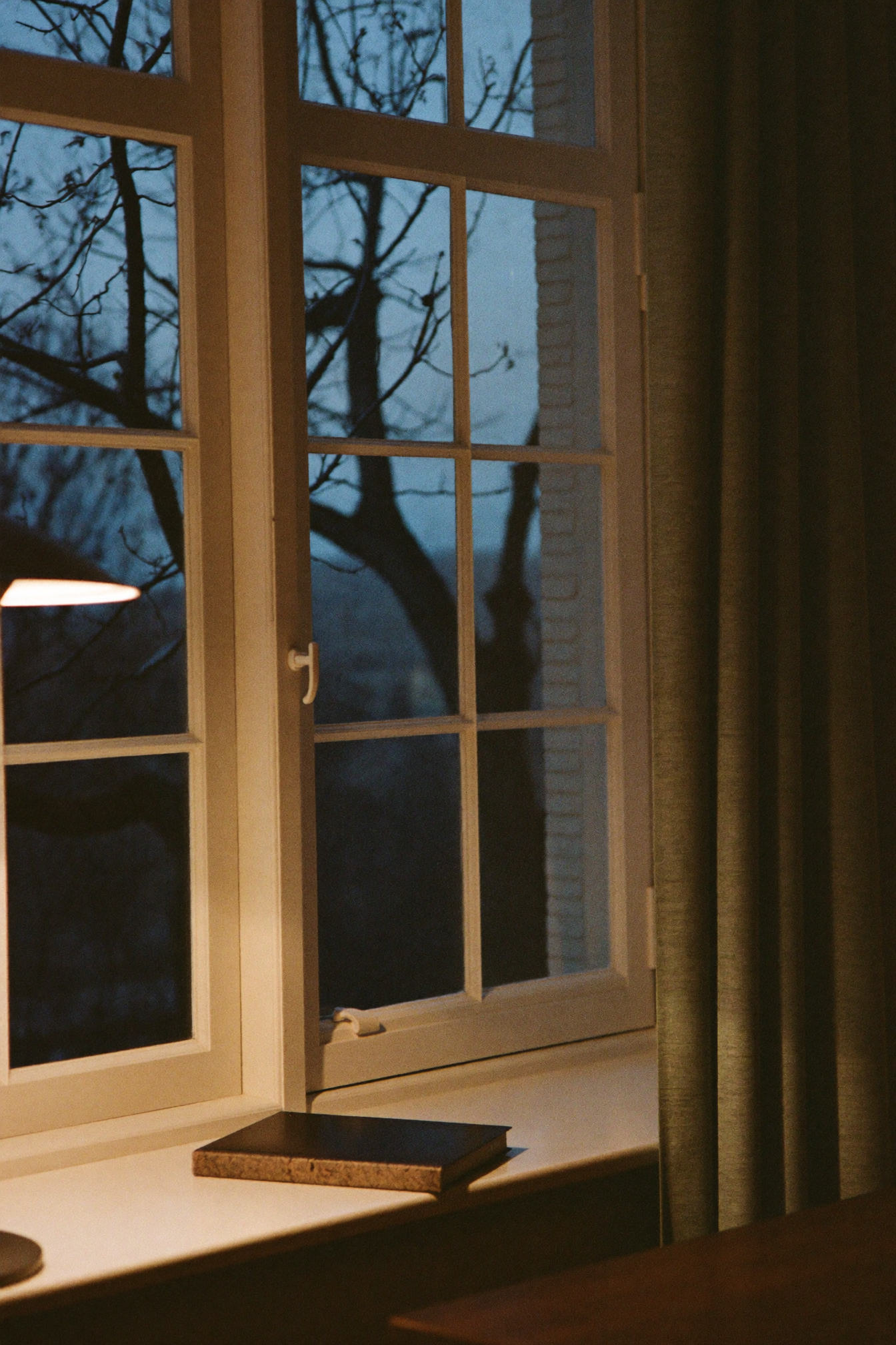 Fenster eines Treuhandbüros in der Abenddämmerung mit geschlossenem Ledger auf der Fensterbank